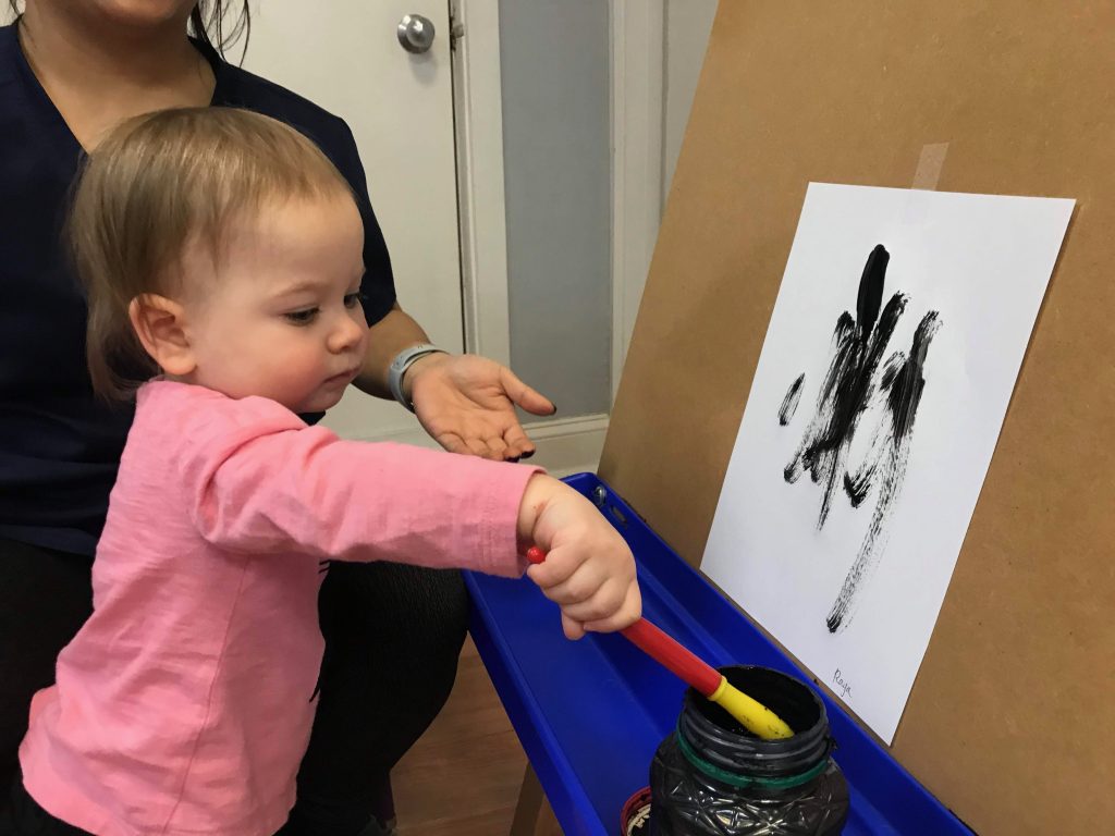 A young child painting at an easel during a session