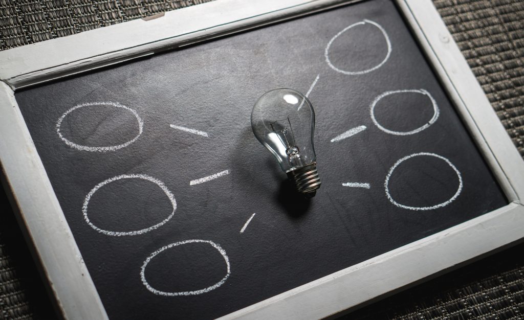 A chalkboard with a lightbulb and connected circles drawn in chalk